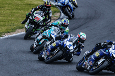 Gruppo di piloti in curva durante gara motociclistica, esempio di progetto gestito da Noline.