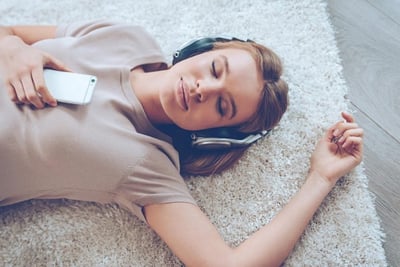 woman laying down with headphones listen to music