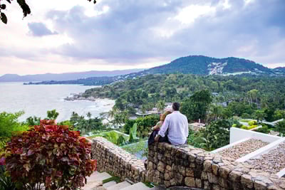 A couple enjoys a romantic moment on a mountaintop overlooking Koh Samui's diverse landscape.
