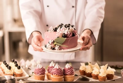 Pastry chef student decorating a cake in baking class