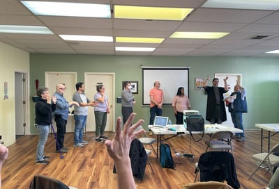 Hand raised in center of photo with people lined up in the background