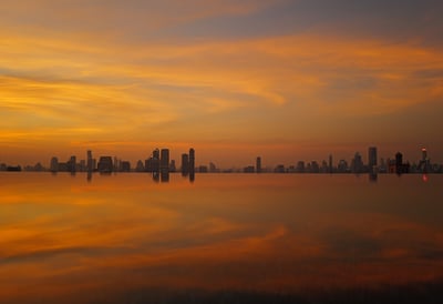 Sunset city skyline of bangkok mirrored on calm water, By ACAT Photos