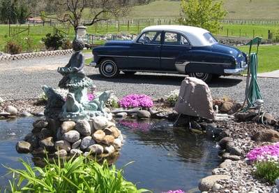 a car parked in a driveway with a statue of a bird on the side of