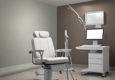 A hospital room with a bed on wheels. The bed is neatly made with white sheets and a brown blanket. The room has pale green walls, a wooden panel with medical equipment including electrical outlets and an IV stand. There are curtains partially drawn on both sides of the bed for privacy, and the flooring is tiled.