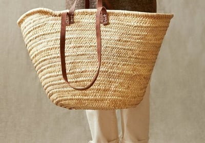 a woman holding a basket weaved basket bag