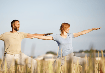 a man and woman doing yoga in the grass