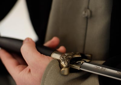 Close-up of a hand drawing a Wudang Jian sword, showing engraved blade and ornate bronze guard.