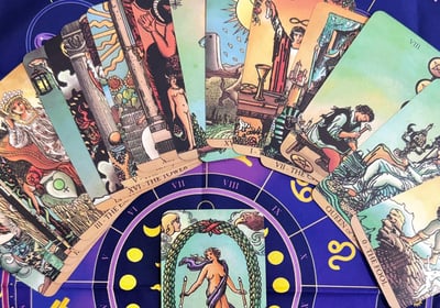 Manos sosteniendo cartas del tarot sobre mesa de madera: El Loco, La Sacerdotisa y El Sol - Lecturas