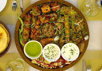 a plate of food with a different types of kebabs and a bowl of dips