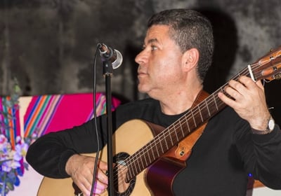 a man in a black shirt playing guitar and singing
