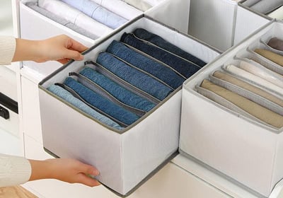 a person holding a drawer full of folded folded folded fabric