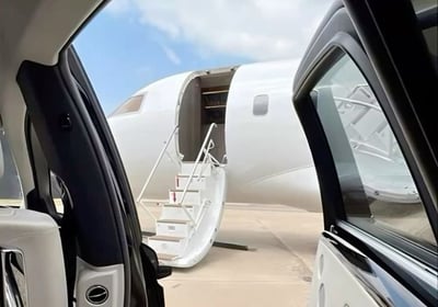 a car with a door open and a plane parked in front of it