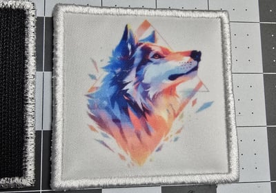 Colorful sublimated patch featuring a geometric watercolor-style wolf head design with embroidered w