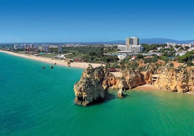 Golden cliffs and turquoise sea of Praia dos Três Irmãos and Praia do Alvor in Algarve, Portugal.
