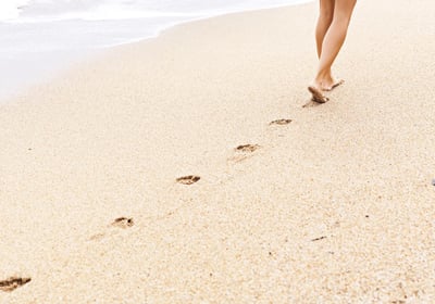 Voetafdrukken in zand op het strand bij de kustlijn.