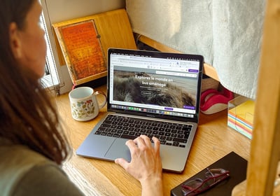 a woman sitting at a desk with a laptop and a cell phone