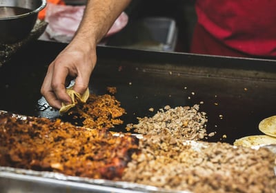 a person is cooking food in a pan on a grill, Street Local at Tacos Mixes Los Angeles