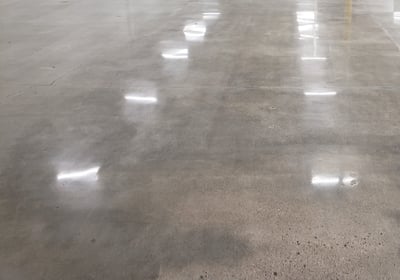 polished concrete in the inside of a building with lights reflecting from it