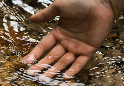Main dans l’eau claire symbolisant l’apaisement mental et la lecture subtile du champ énergétique