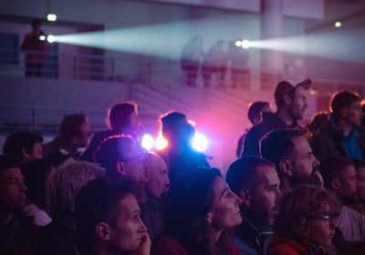 Public captivé devant une projection, éclairé par des faisceaux lumineux en ambiance immersive