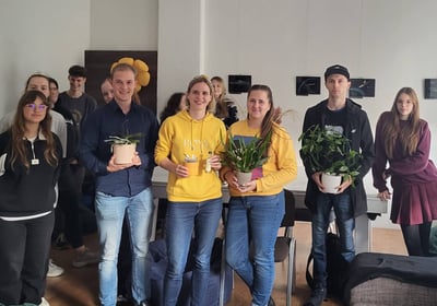 Orchidėjų laboratorijos renginio dalyviai sustoję kartu su lektore Vilte. Rankose laiko orchidėjas.