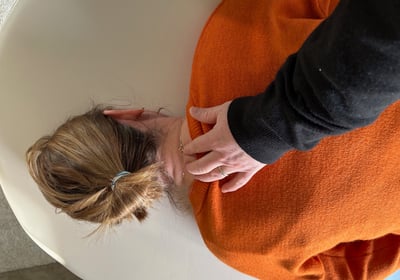 a woman in orange lying on her stomach, the patrician with her hand on her occiput