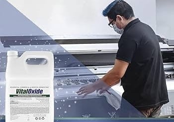 A man in a black shirt is sanitizing a machine.
