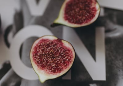 Close-up of ripe figs placed on a reflective fashion magazine spread