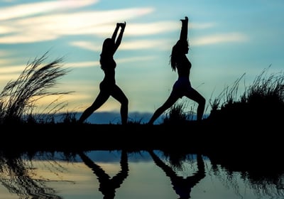 two people doing yoga poses in the evening