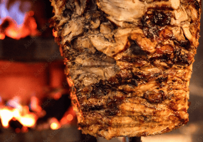 Shawarma cooking on a vertical rotisserie at Taouk Watford, with juicy layers of meat.