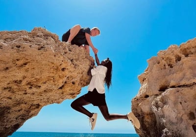 A man and woman are standing on a rock formation
