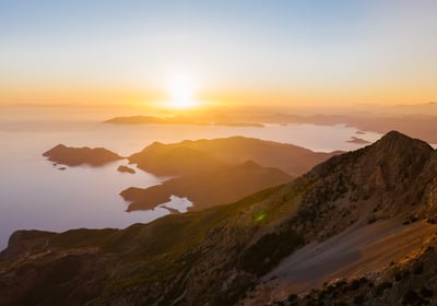 a mountain scene with a sunset over the ocean
