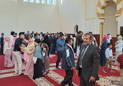 a group of people standing in The Imam Malik Mosque