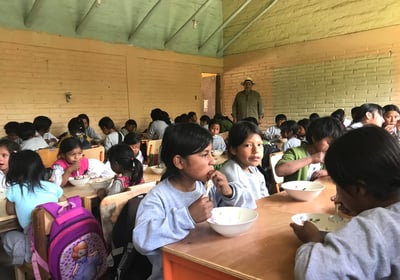 a group of children eating food in a classroom