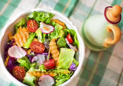 a bowl of salad with tomatoes and dressing dressing
