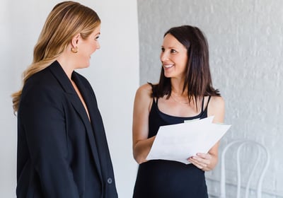 Two women conversing holding a planning paper