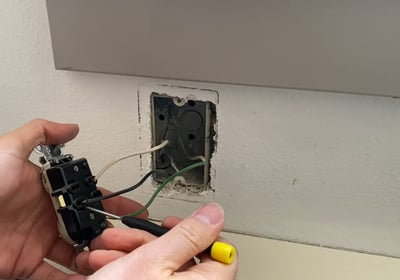 Using a tiny screwdriver to remove the wires from the receptacle without cutting them