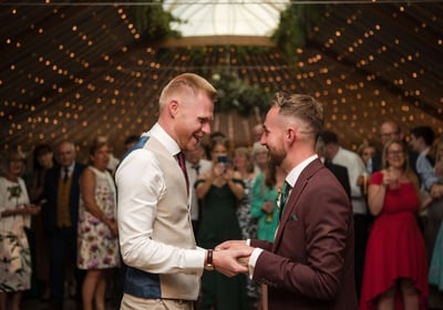 Two men hold hands on their wedding day