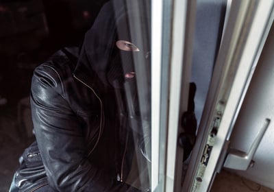 man in mask breaking into home through an unlocked window