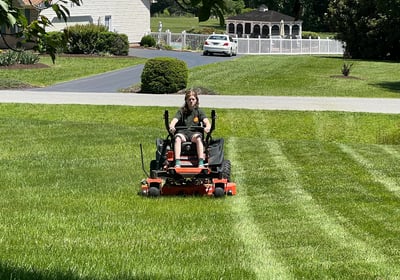 a man riding on a lawn mower in a yard