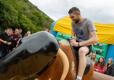 A man riding a rodeo bull at Cwmdu and District Show infront of a crowd
