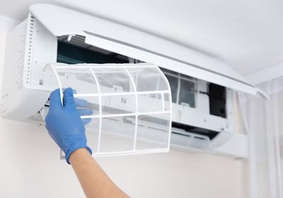 a person in gloves and gloves is holding a filter white of a air conditioner