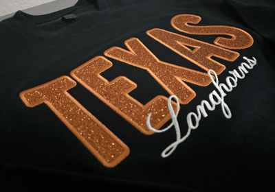Black sweatshirt with glitter TEXAS Longhorns appliqué – custom collegiate embroidery by Stitch & Th