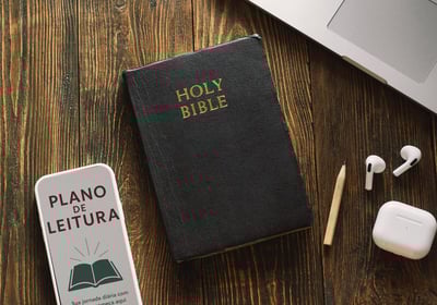 Bíblia com capa Holy Bible ao lado de plano de leitura, fones de ouvido e lápis sobre madeira
