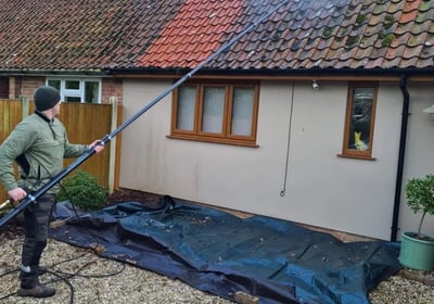 a professional roofer removing moss from a London property in need of a roof clean