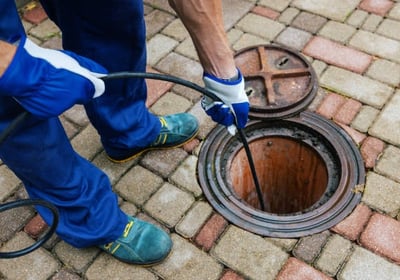 plumber cleaning a sewer line with a hose pump