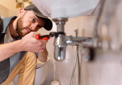 plumber focusing very hard while he is turning a pipe under a sinkj