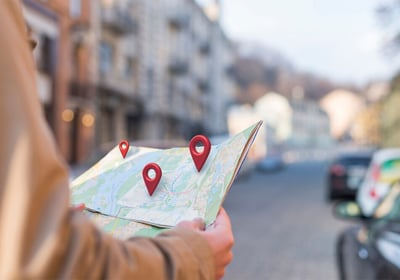 Personne tenant une carte avec des repères de localisation.