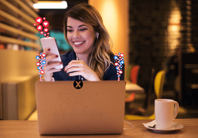 a woman sitting at a table with a cell phone and a laptop with social media icons