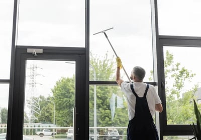 a man cleaning a window with a broom and a broom